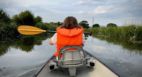 A lady in a canoe complete with life jacket and paddle.