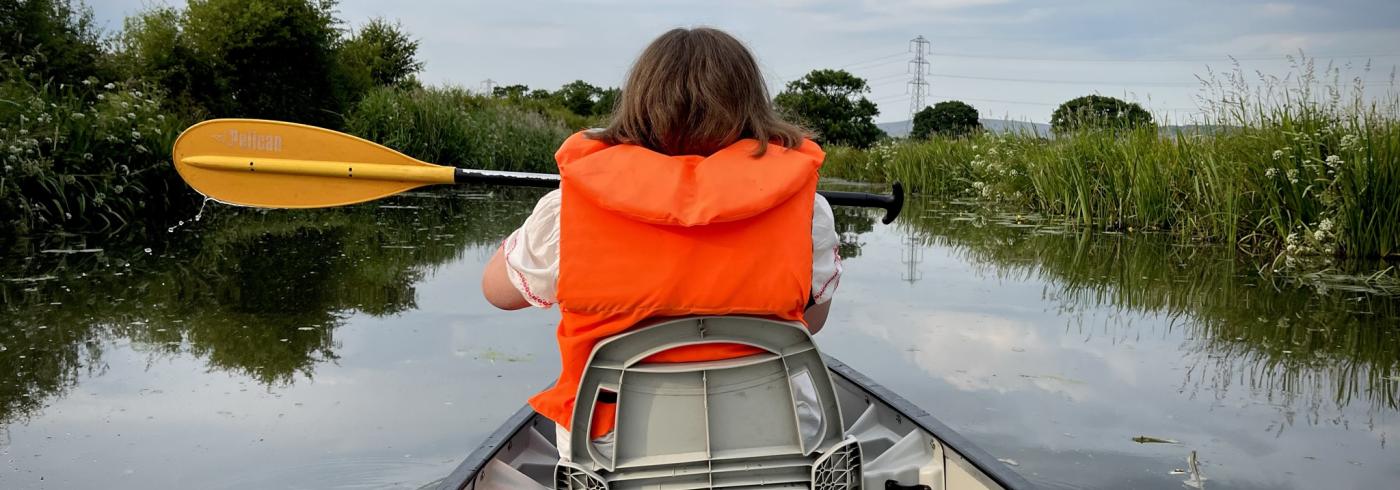 A lady in a canoe complete with life jacket and paddle.